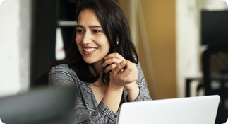 Woman dressed in business attire, smiling and chatting with a colleague.